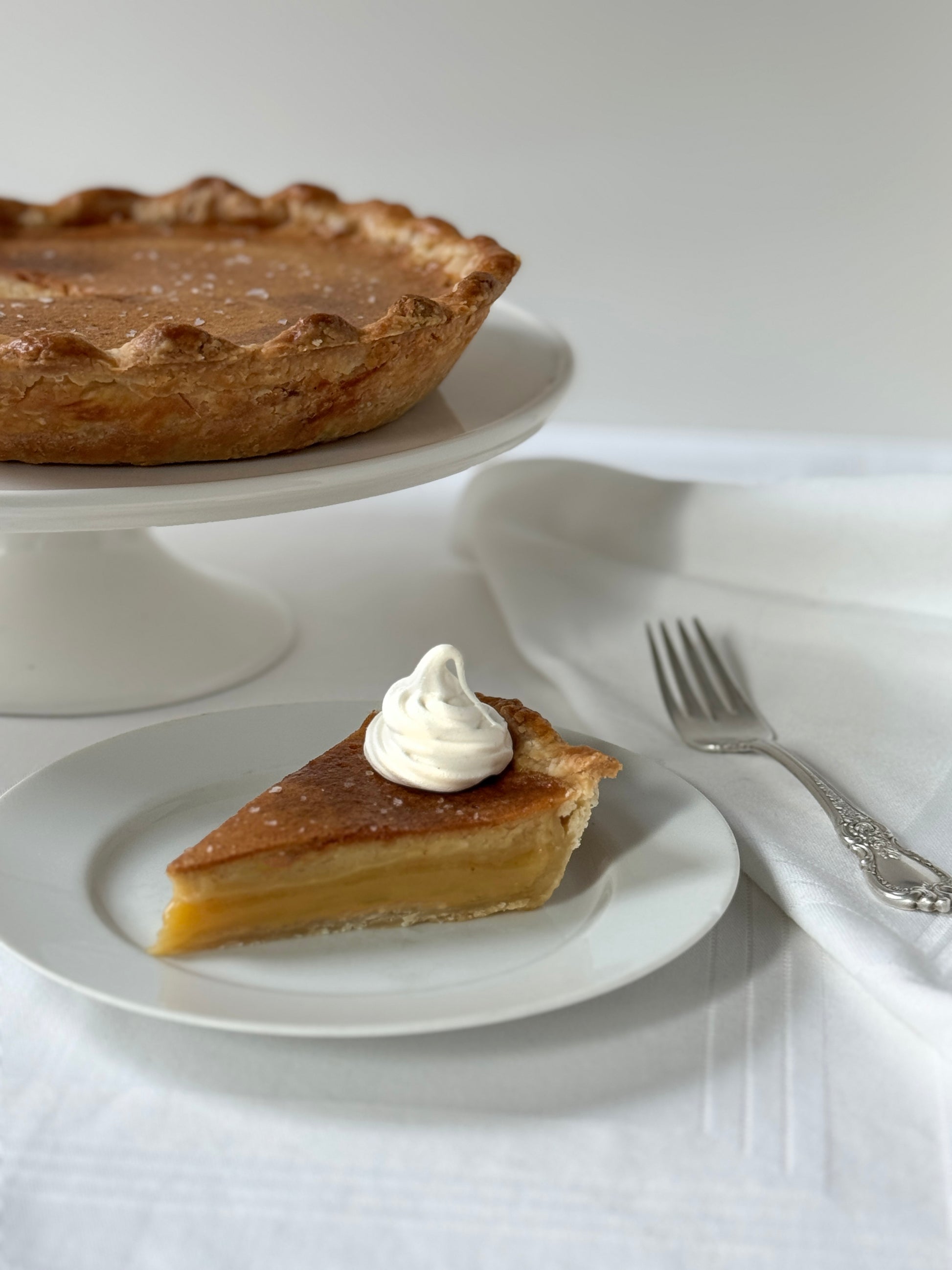 Slice of salted honey custard pie with sea salt on white plate