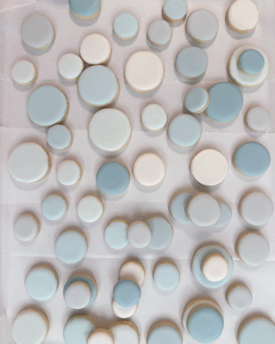 Assorted iced sugar cookies in soft blue and ivory tones in varied small round sizes